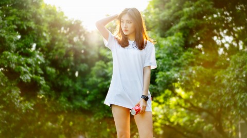 selective focus photo of woman standing behind green trees